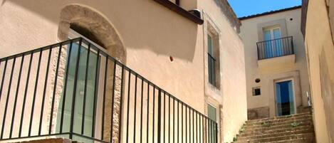 A stone staircase leading to a building with a balcony.