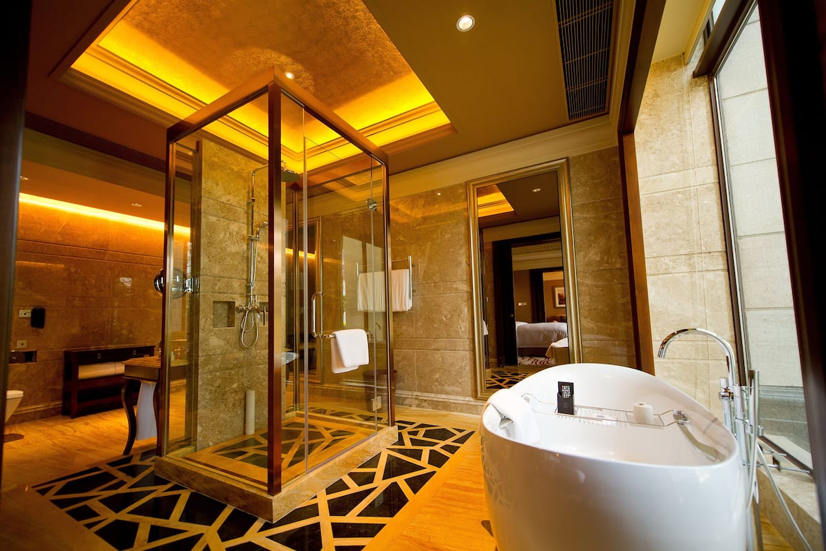 A modern bathroom with a glass-enclosed shower, a freestanding bathtub, and a patterned floor.