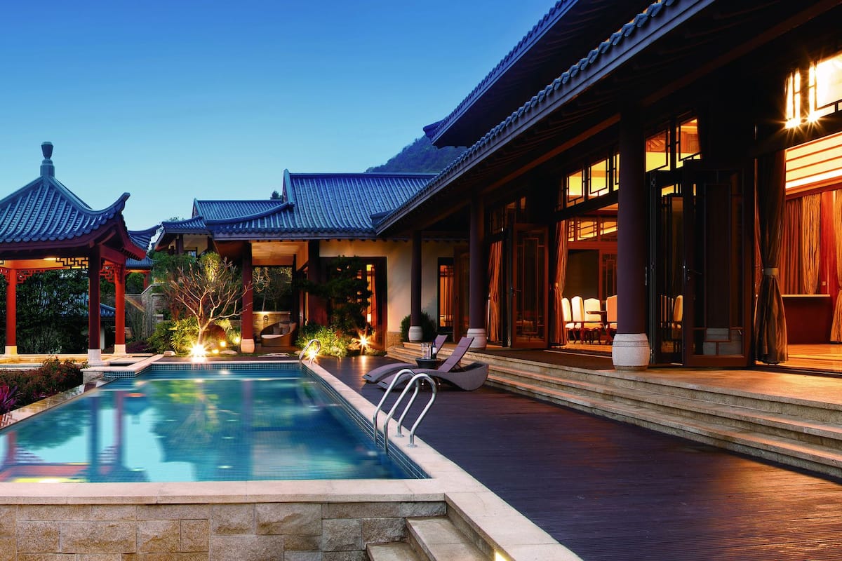 A traditional building with a pool and a view of mountains.