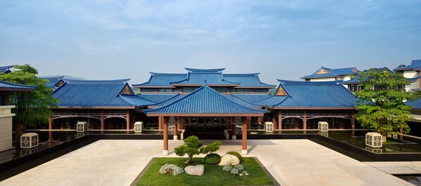 A traditional building with blue tiled roofs and a courtyard with stone lanterns and a water feature.