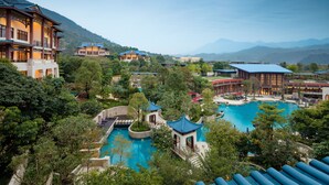 A resort with multiple buildings, a large swimming pool, and lush greenery. - Imperial Springs (Guangzhou)