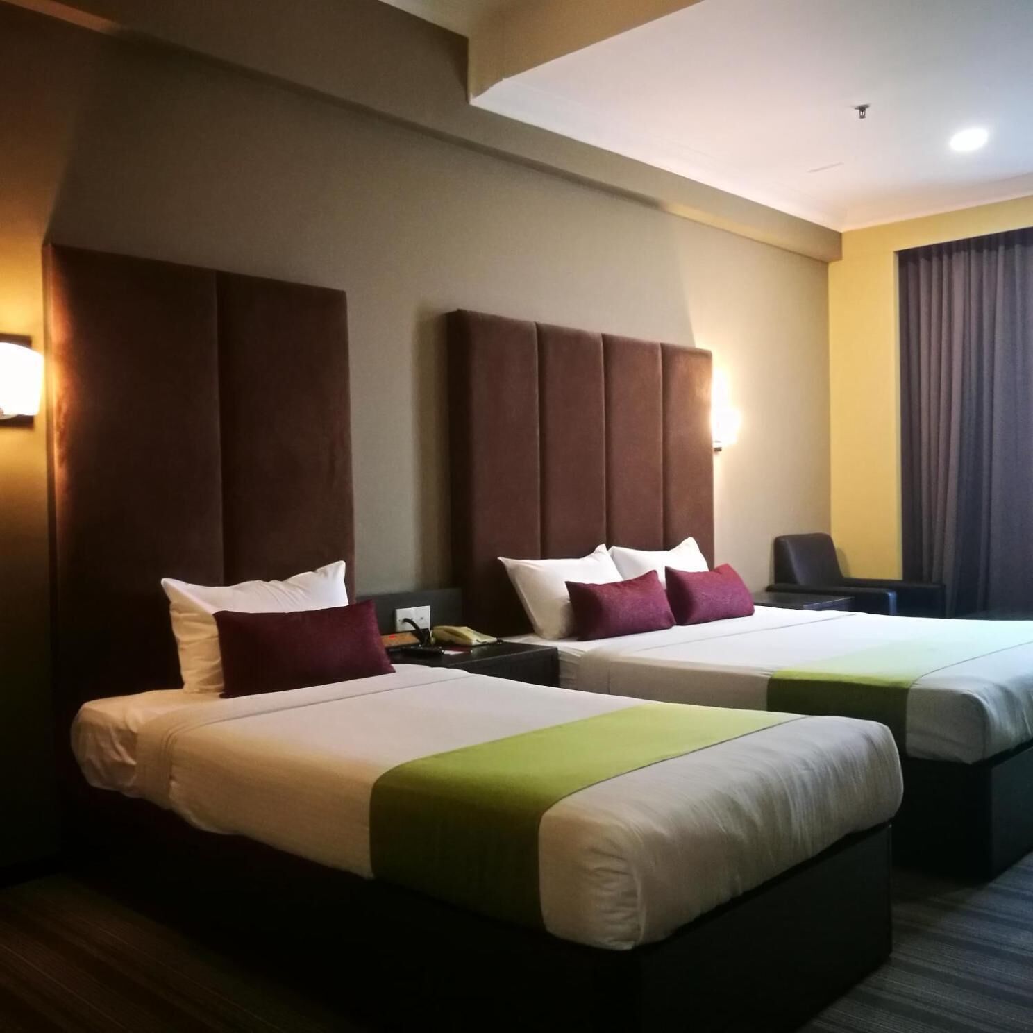 A hotel room with two beds, a desk, and a chair.