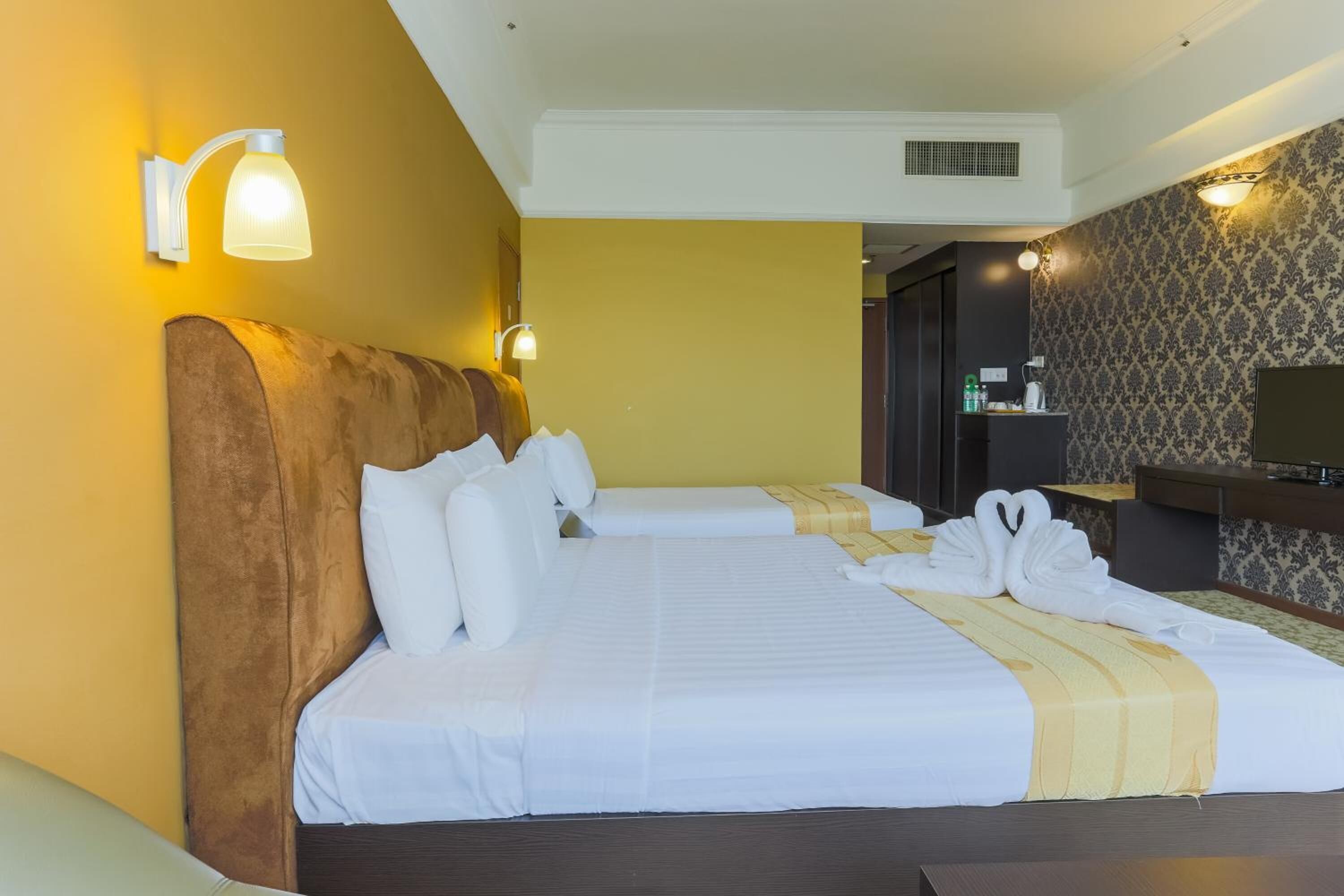A hotel room with two beds, a wooden headboard, white bedding, and a minibar.