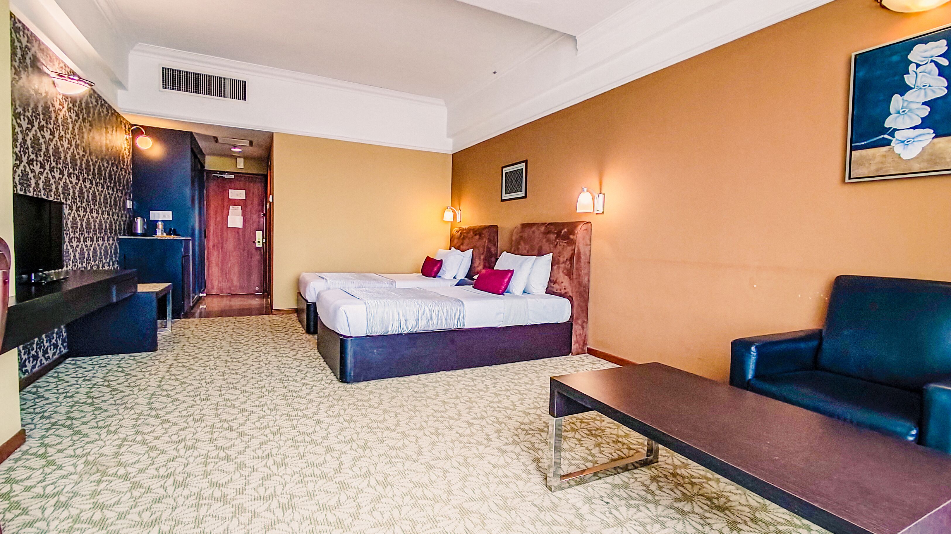 A hotel room with a bed, a desk, a chair, and a painting on the wall.