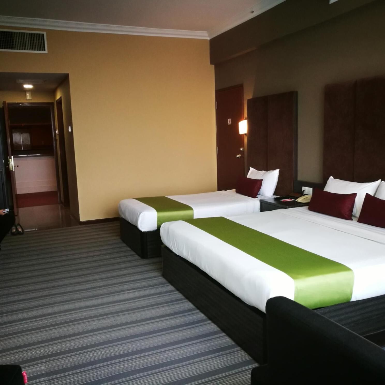 A hotel room with two beds, a desk, and a wardrobe.
