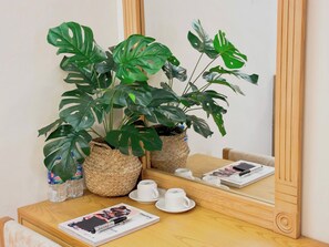 Une table en bois, avec un magazine, deux tasses blanches et un grand miroir qui reflète la pièce.