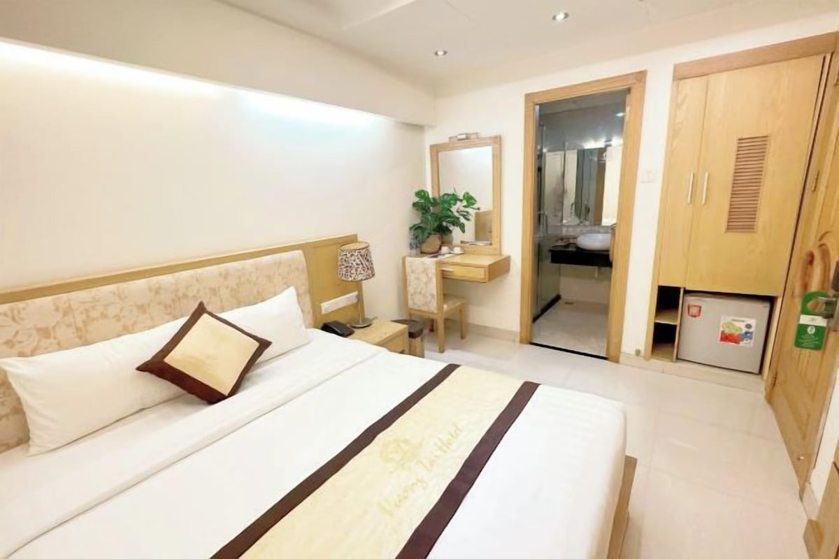 Una habitación de hotel con cama, mesita de noche, espejo, escritorio y armario.