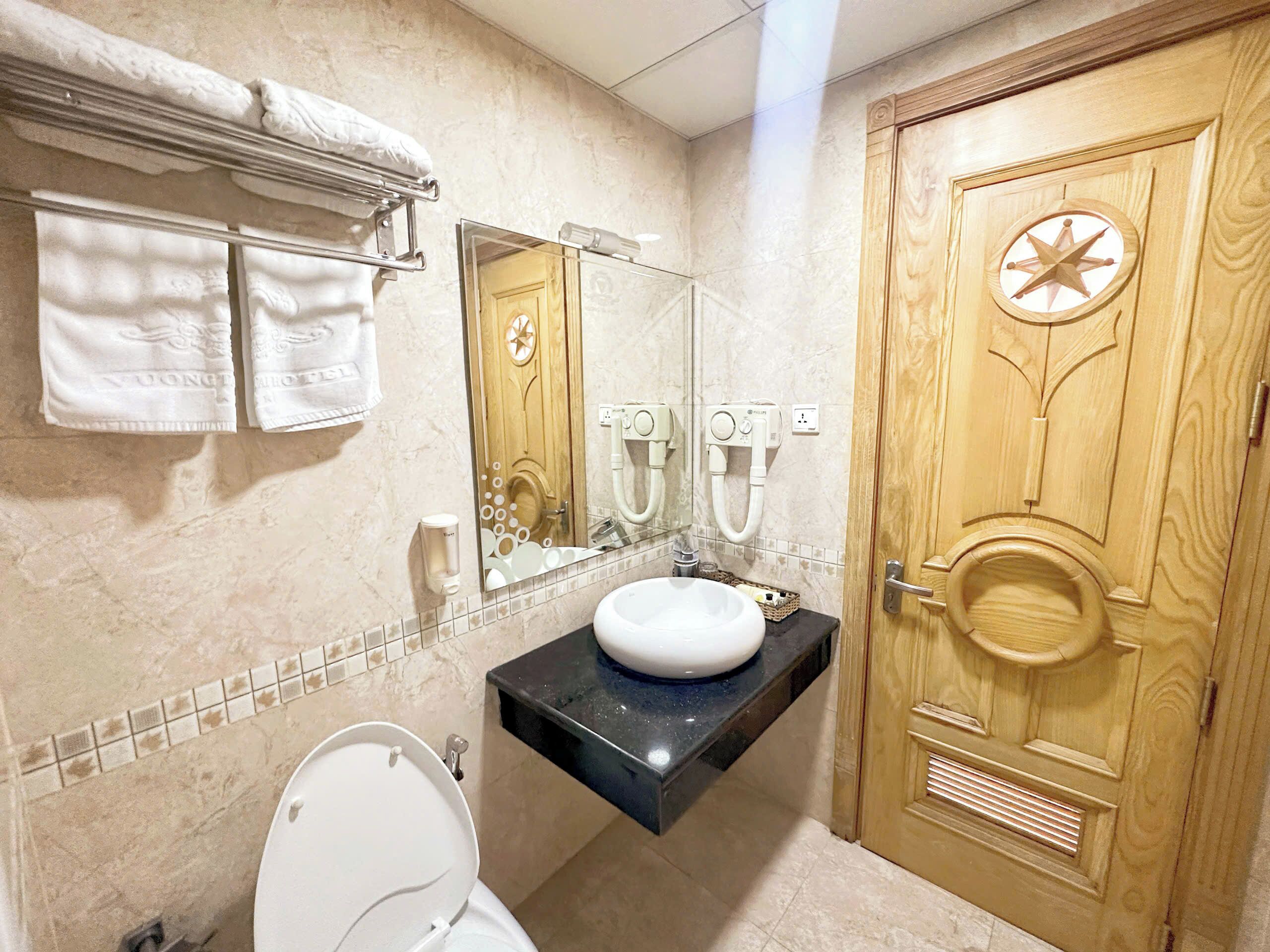 Une salle de bain équipée de toilettes, d’un lavabo, d’un porte-serviettes et d’un miroir.