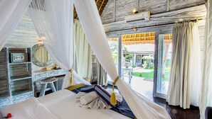 A bedroom with a canopy bed, a desk, and a view of the garden.