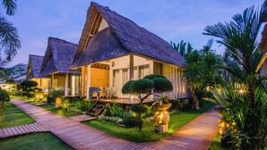 A resort with thatched-roof cottages, a wooden pathway, and well-maintained tropical landscaping.