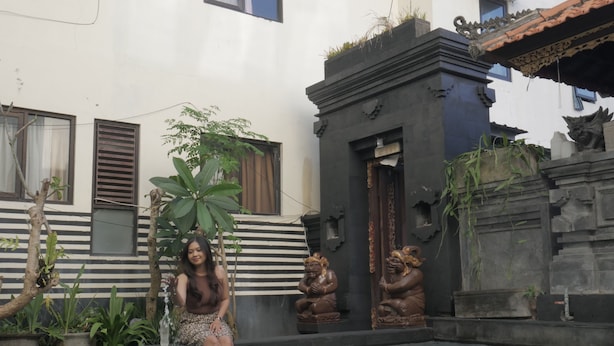 Una persona sentada en una piscina con un edificio decorativo al fondo.