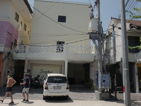 A building with a sign for 'Sundanta Inn' and a white car parked in front.