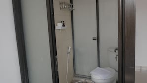 Un baño con inodoro, cabina de ducha y lavamanos.