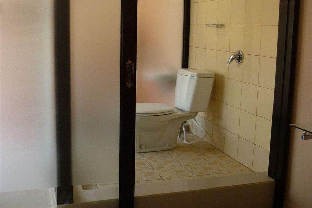 A bathroom with a toilet, a shower, and a tiled floor.