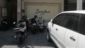 Un aparcamiento con varias motocicletas y un coche blanco.