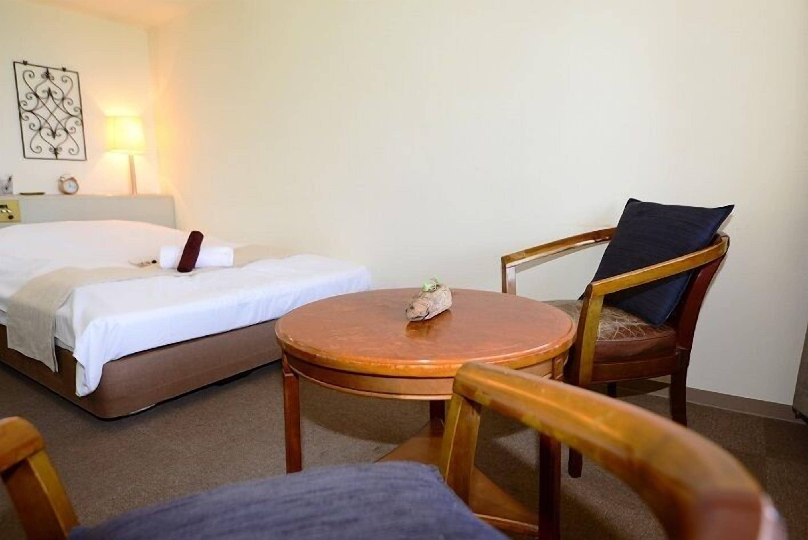 Una habitación de hotel con una cama, una mesa redonda de madera y dos sillas de madera.