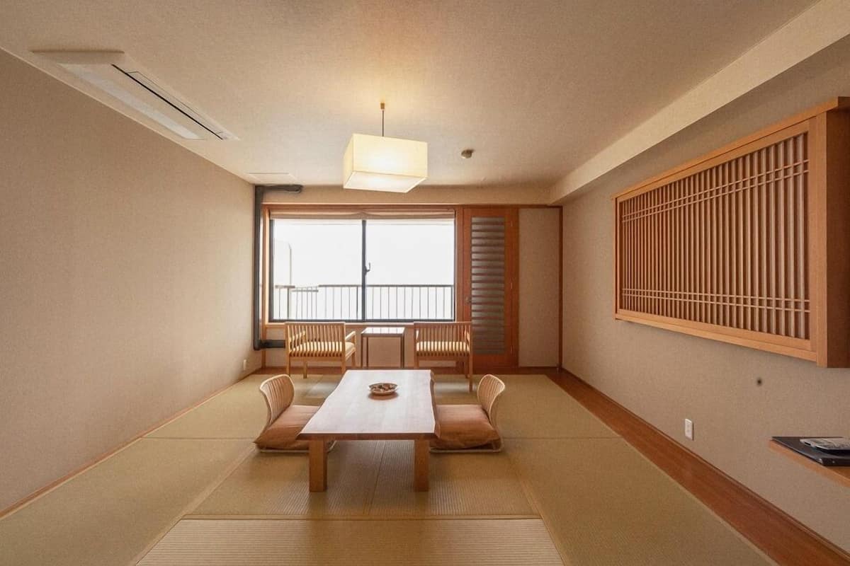 Una habitación japonesa tradicional con suelo de tatami, una mesa baja y puertas correderas.
