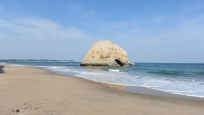 Una playa con una gran formación rocosa en el agua.