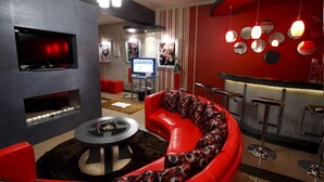 A modern living room with a red sofa, a TV, and a bar area with stools. - Victoria Court Suites - Pasig (Pasig)