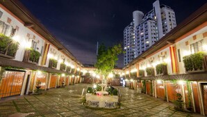 A courtyard with a fountain, surrounded by buildings with balconies and potted plants. - Victoria Court Suites - Pasig (Pasig)