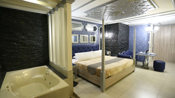 A modern hotel room with a large bed, a separate bathroom, and a dining area. - Victoria Court Suites - Pasig (Pasig)
