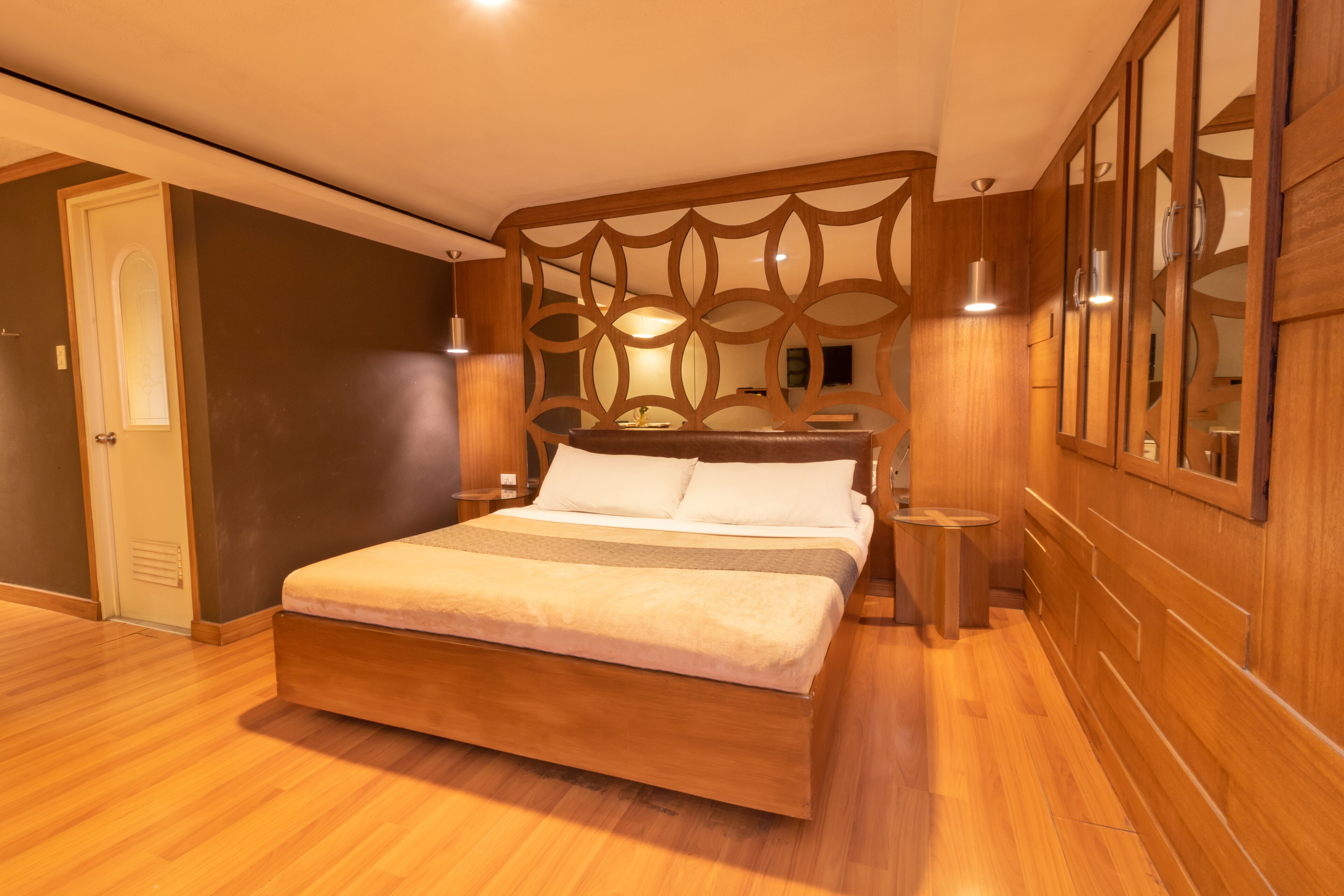 Un dormitorio moderno con una cama de madera, un cabecero decorativo y un espejo grande en la pared.
