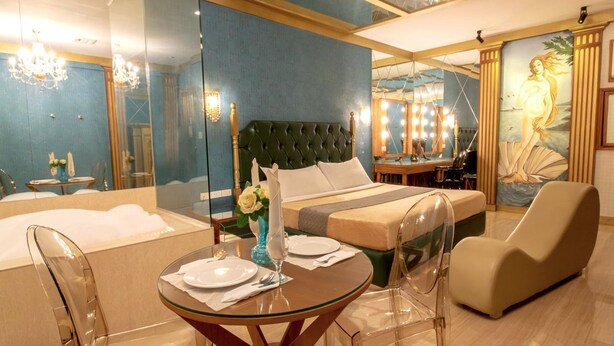 A modern hotel room with a large bed, a sitting area, and a dining table. - Victoria Court San Fernando - Pampanga (San Fernando)
