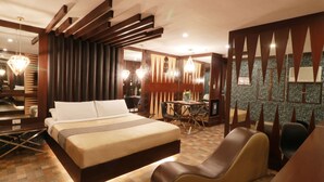 A hotel room with a large bed, a desk, and a dining area. - Victoria Court San Fernando - Pampanga (San Fernando)
