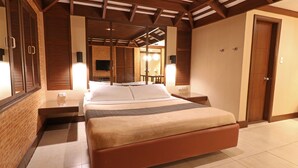 A spacious bedroom with a large bed, wooden headboard, and a brick accent wall. - Victoria Court San Fernando - Pampanga (San Fernando)