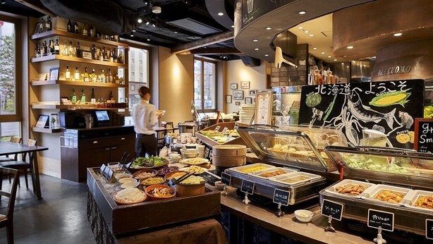 A buffet area with various food options and a bar with shelves of bottles. - Daiwa Roynet Hotel Sapporo Susukino (Sapporo)