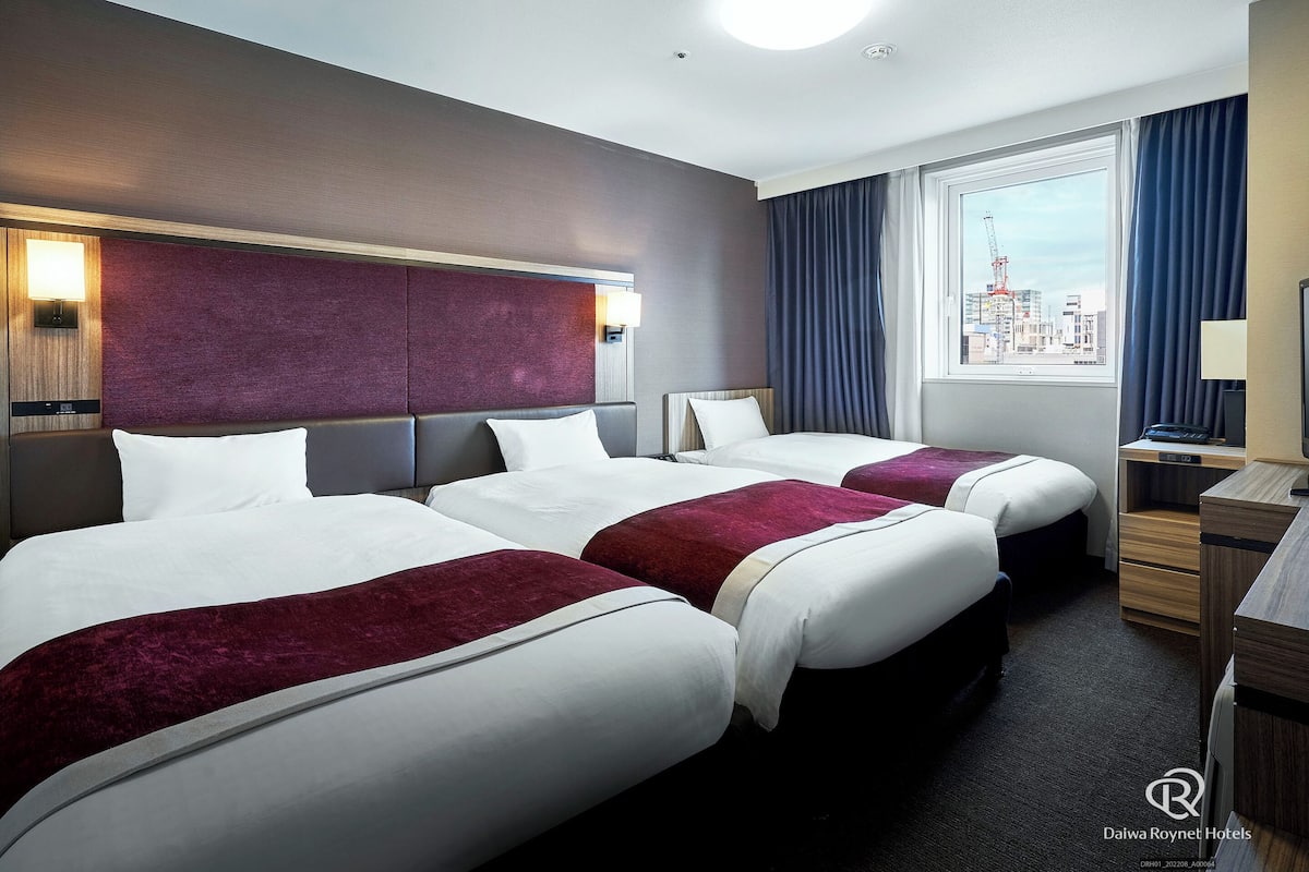 Ein Hotelzimmer mit zwei Betten, Stadtblick, Schreibtisch und Nachttisch.