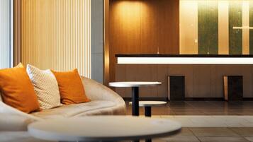 Eine moderne Hotelhalle mit einer Couch, einem kleinen Tisch und einer Rezeption.