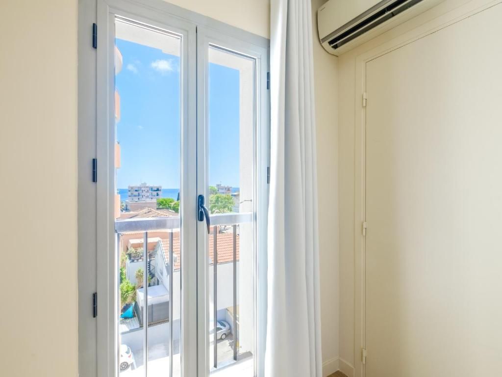 A room with a sliding glass door leading to a balcony, an air conditioning unit mounted on the wall, and a closed door.