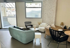 Un salon moderne avec un canapé, des fauteuils, une table basse et une vue sur l’extérieur.
