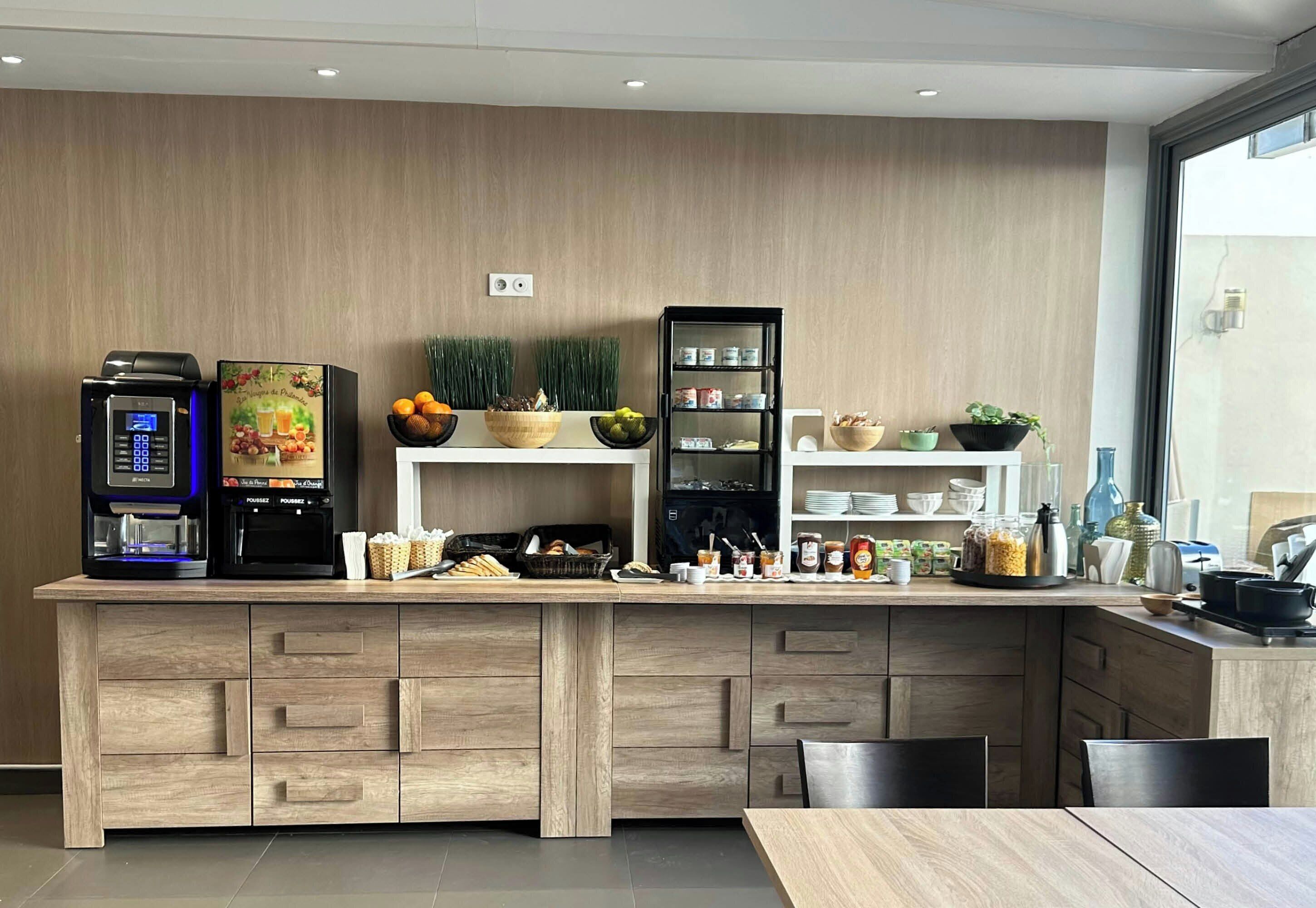 A modern kitchen with a built-in coffee machine, a fruit bowl, and a variety of condiments on open shelves.