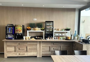 Een moderne keuken met een ingebouwde koffiemachine, een fruitschaal en diverse kruiden en specerijen op open planken.