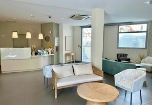 Un moderno vestíbulo de hotel con mostrador de recepción, zona de estar y ventanas amplias.