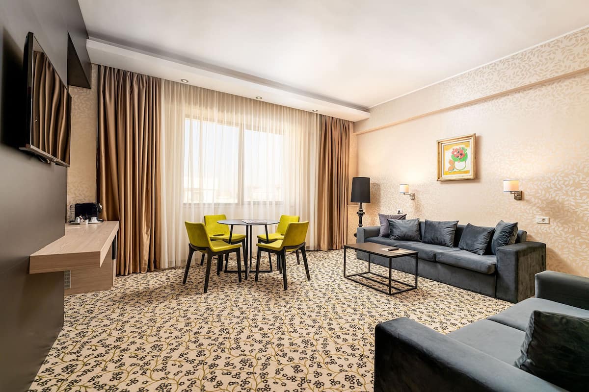 A hotel room with a dining area, a sofa, and a coffee machine.