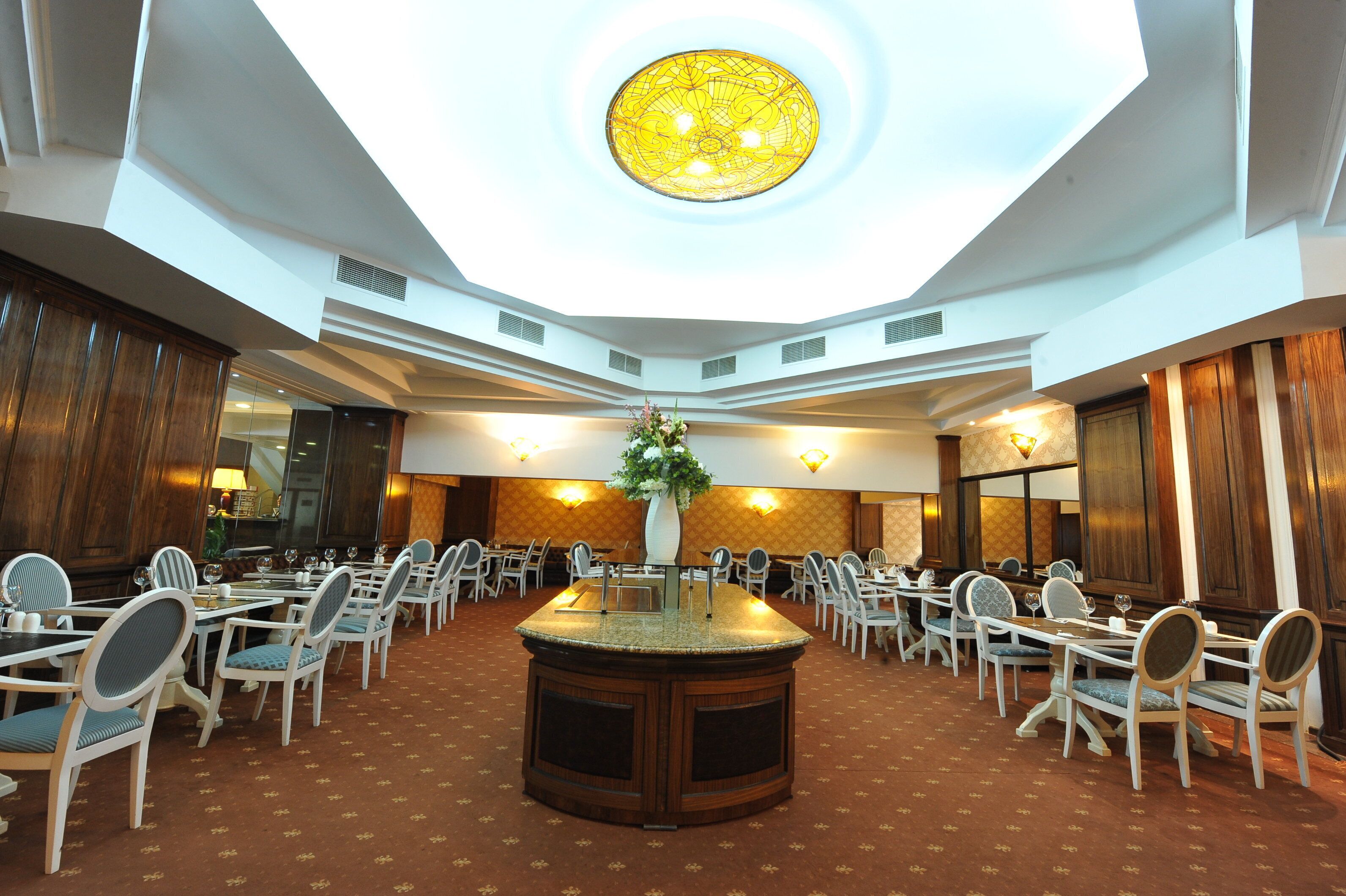 A spacious conference room with a central island, multiple tables, and chairs arranged for meetings.