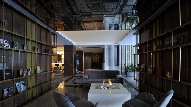 Un interior moderno con una zona de estar central, estanterías y una chimenea.