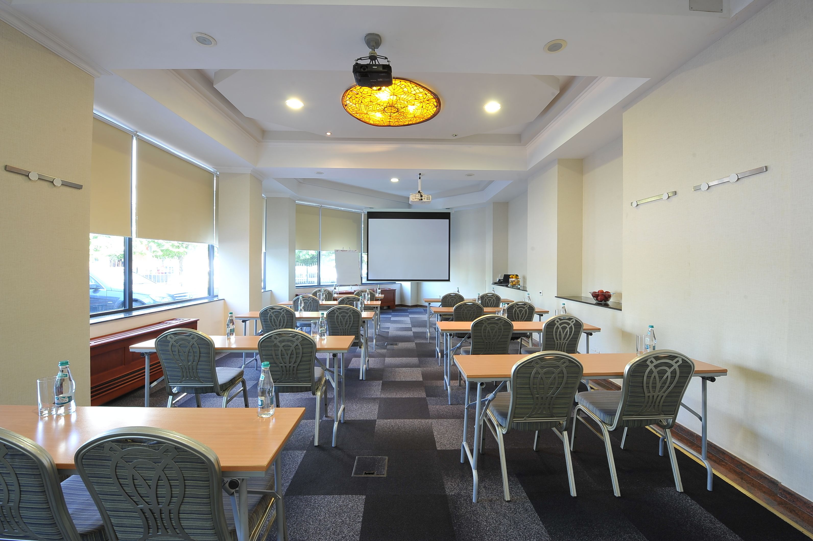 A conference room with tables and chairs, a projector screen, and a large window.