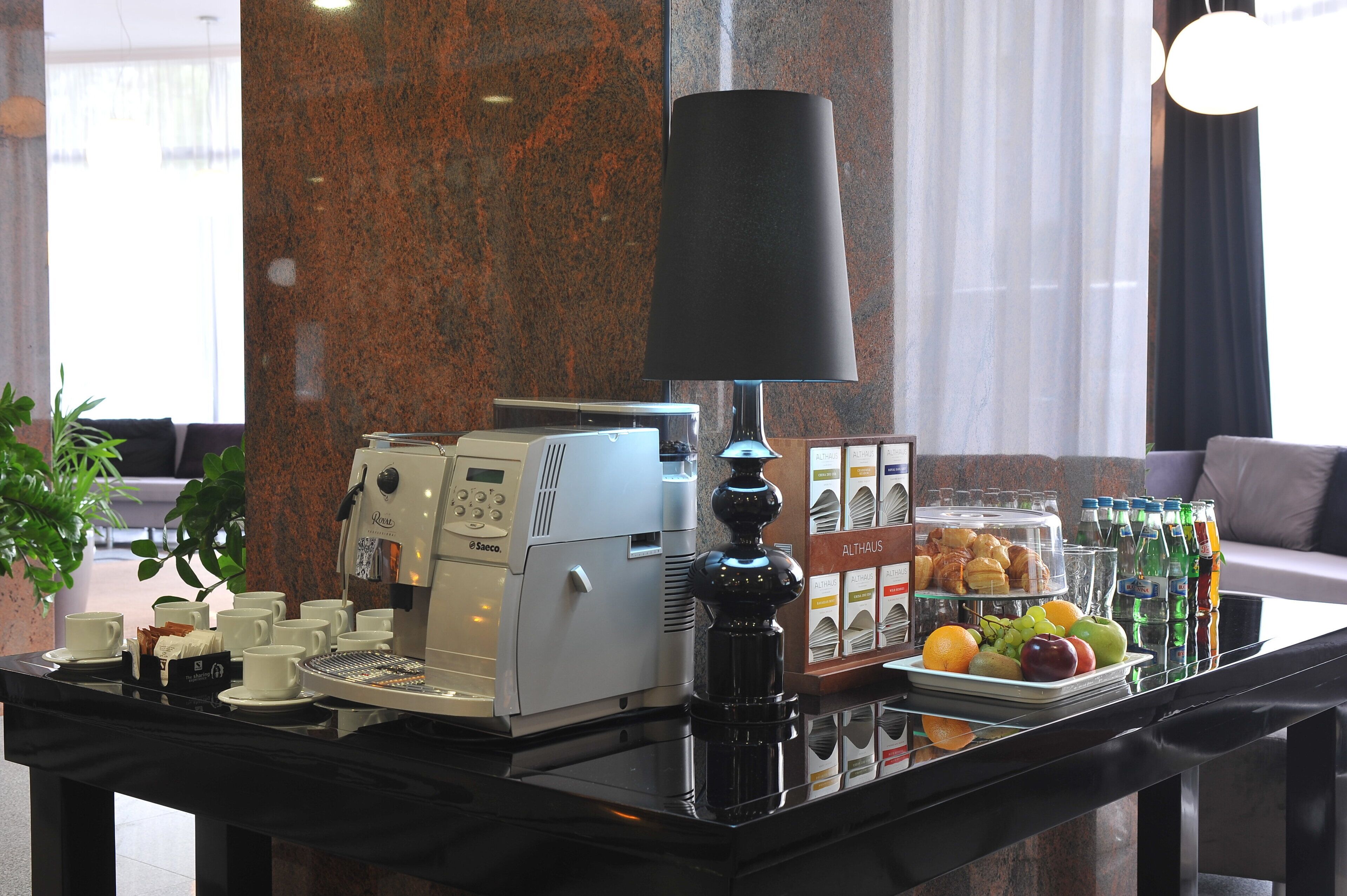 Een ontbijtbuffet met een koffieapparaat, een lamp en een presentatie van fruit en sap.