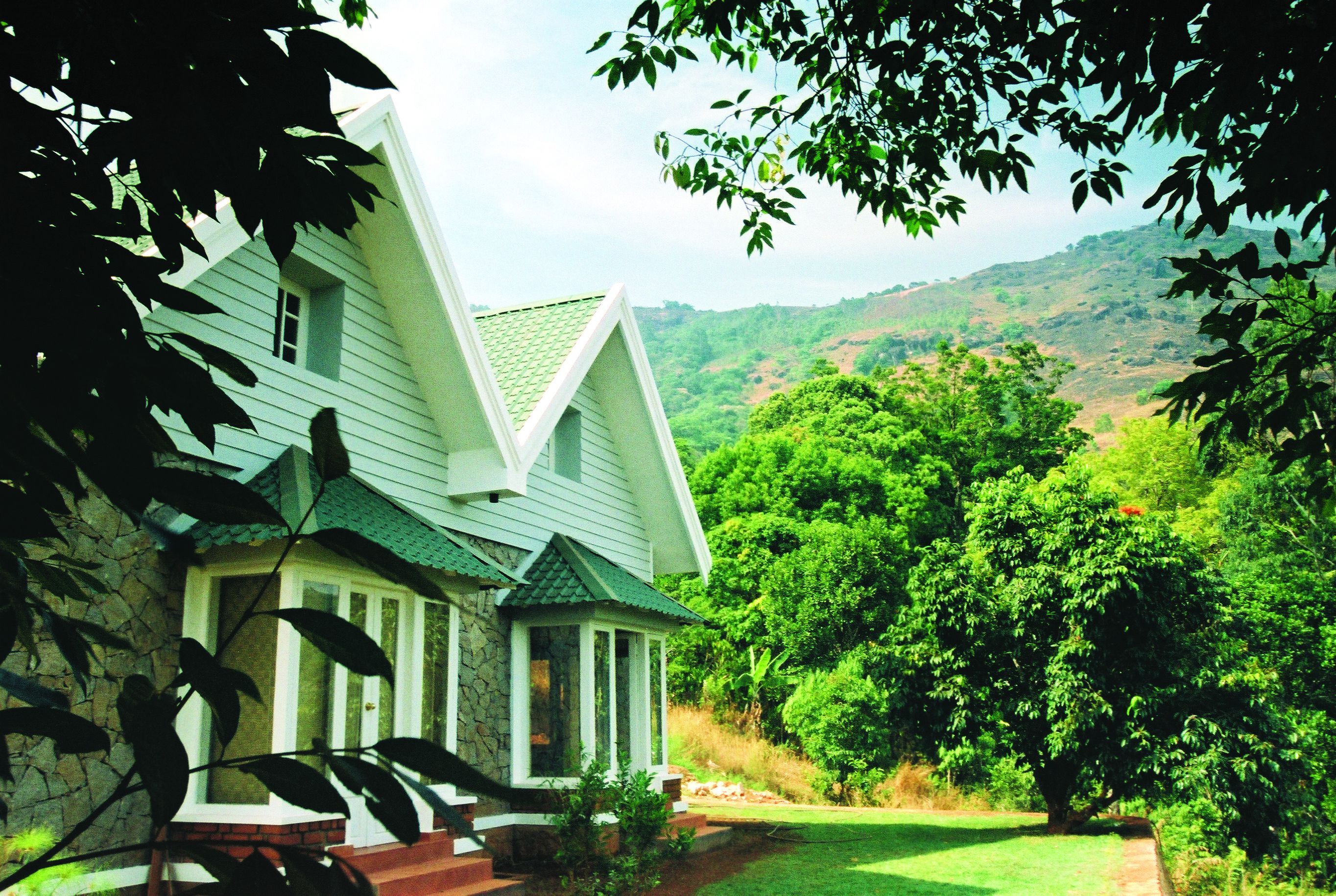 A house with a stone foundation, a green roof, and a front porch.