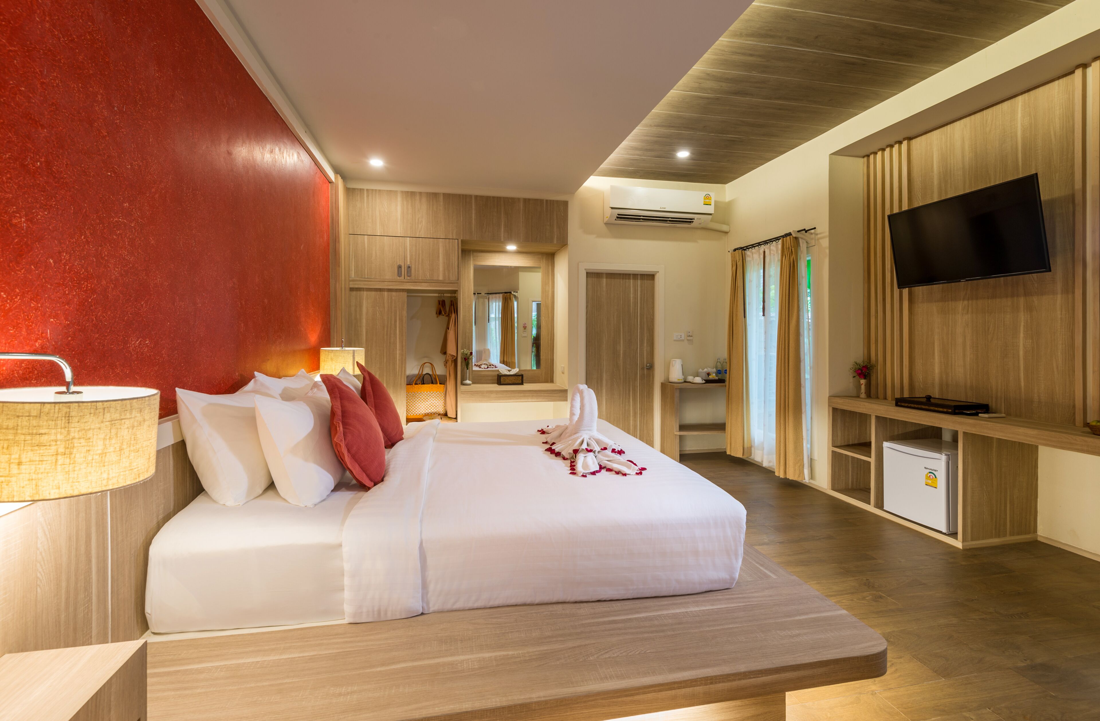 A modern hotel room with a large bed, a TV, a desk, and a minibar.