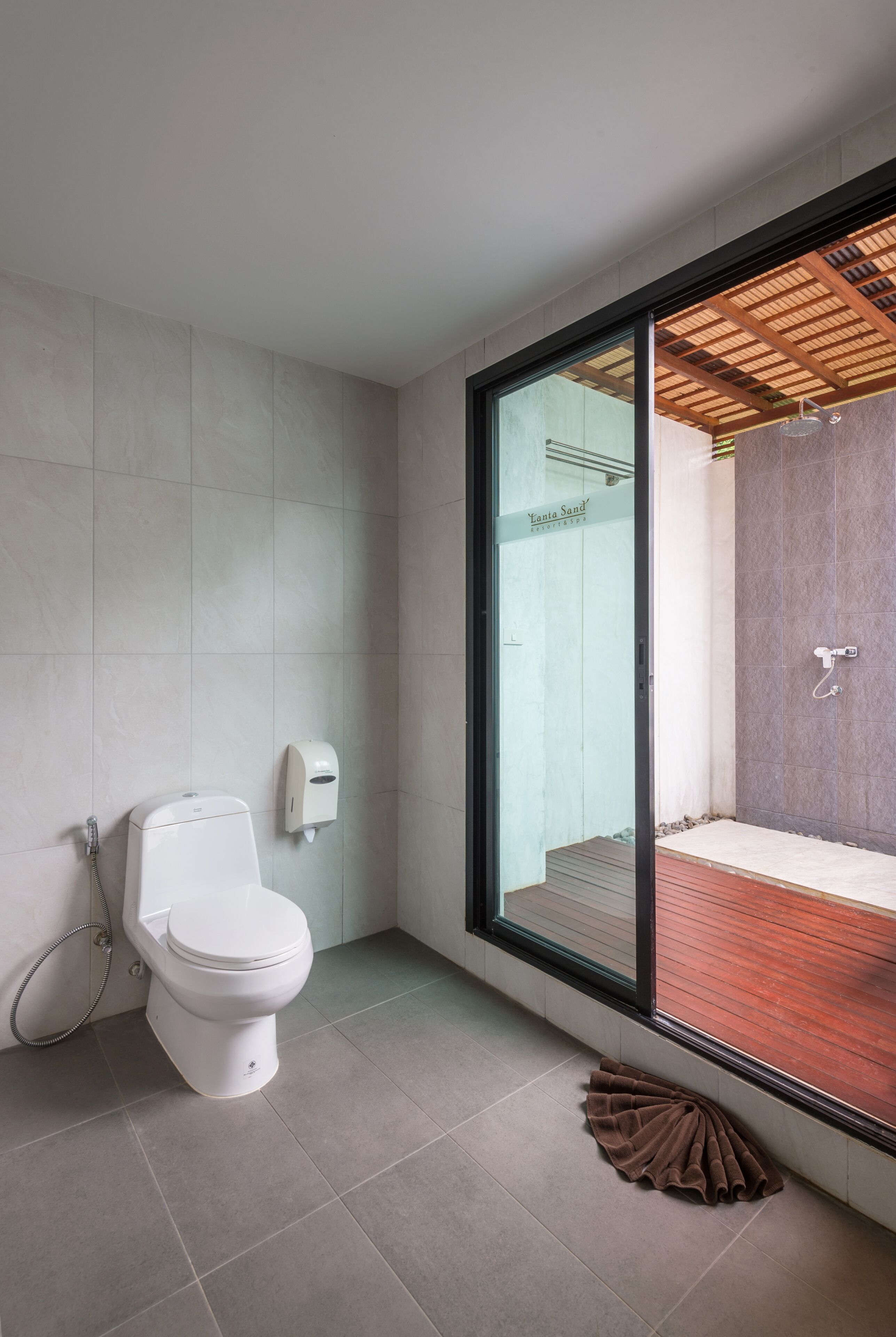 A modern bathroom with a toilet, a hand dryer, and a shower area visible through a glass door.