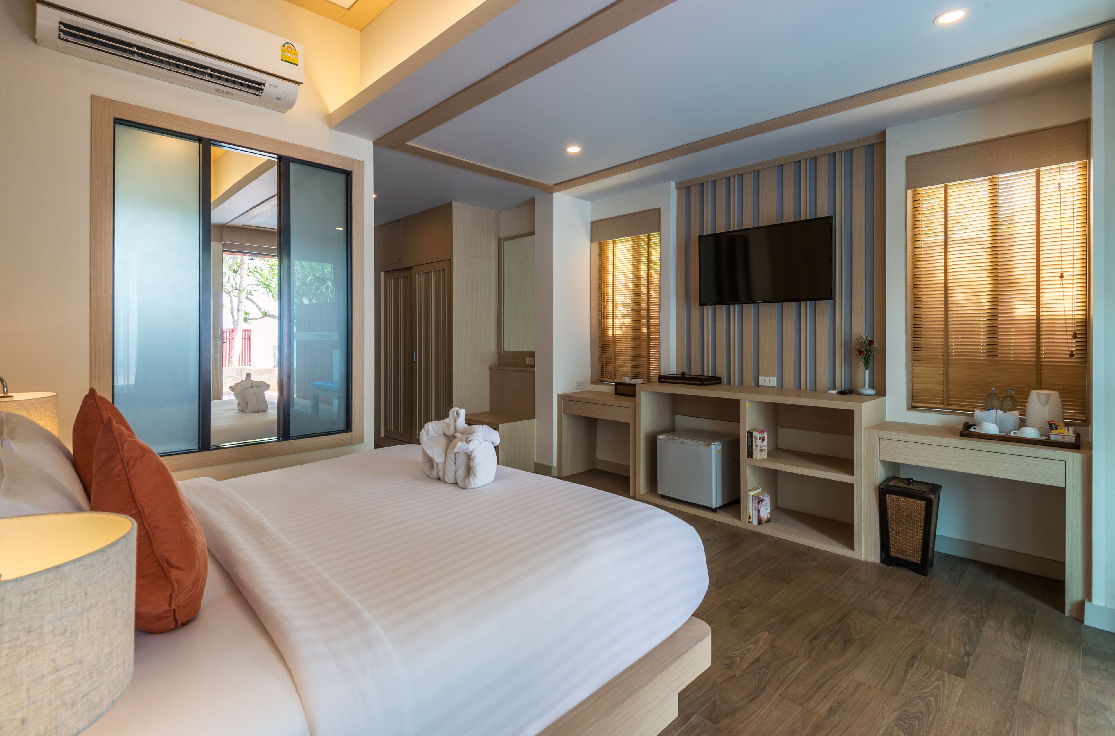Una habitación de hotel con una cama grande, un escritorio, un televisor y vistas al exterior.