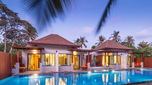 Un resort moderno con piscina, dos villas para huéspedes y una valla de madera.
