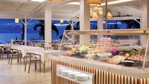 A buffet with various food items and a view of the ocean at dusk. - Coral Azur Beach Resort (Mont Choisy)