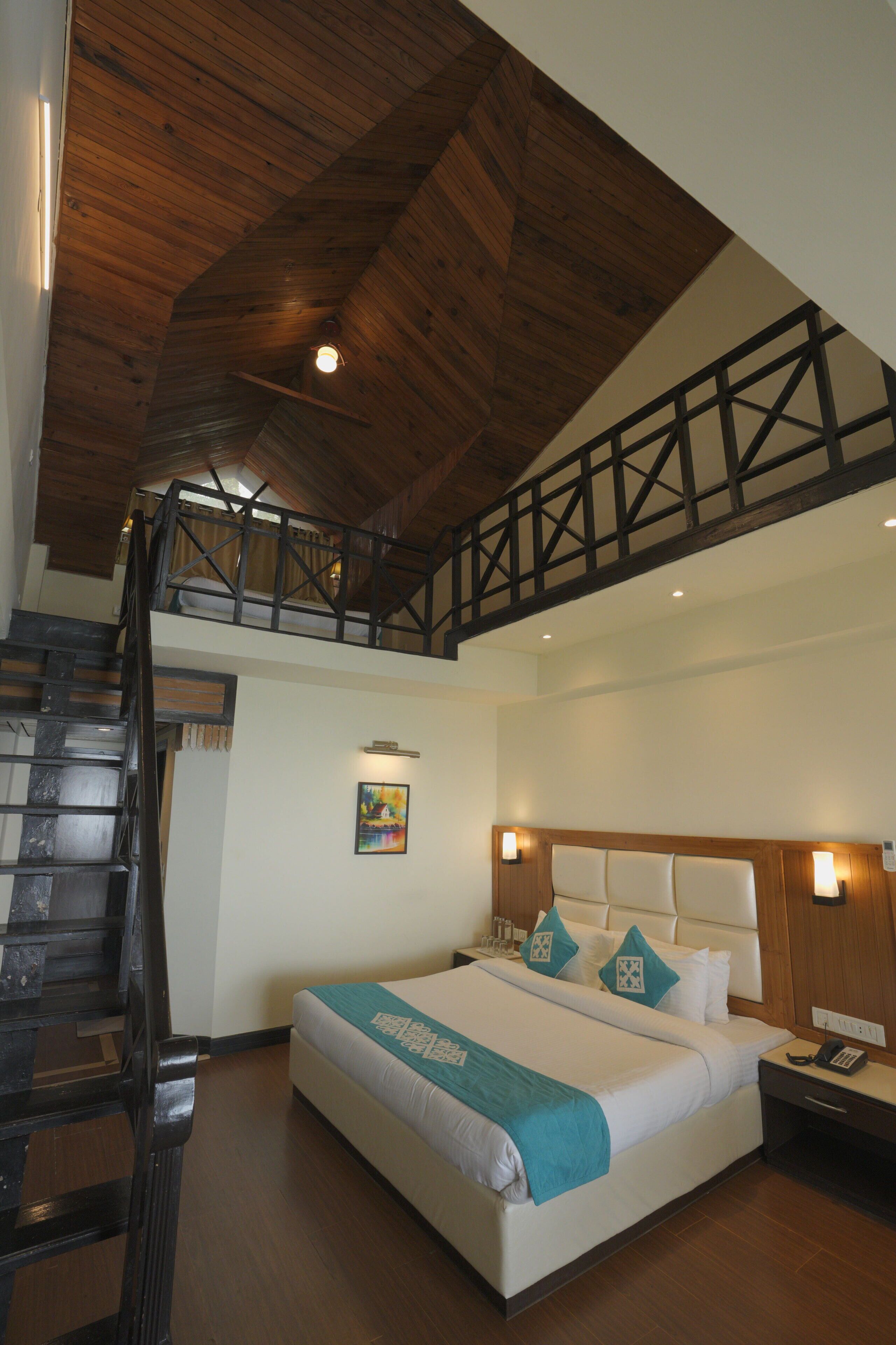 Ein Schlafzimmer mit einem großen Bett, Holzbalkendecke und einer Treppe, die in ein Obergeschoss führt.