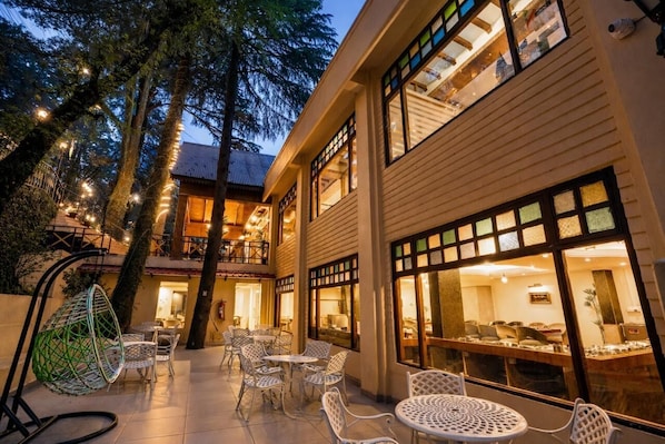 A hotel with outdoor seating, large windows, and a balcony.